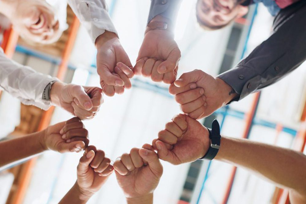 A diverse group of business people united in a circle, holding hands to represent unity and cooperation.